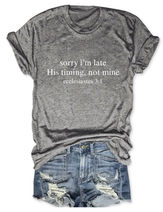 Flat lay di t-shirt grigia con tipografia religiosa bianca e shorts di denim