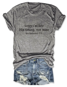 Dettaglio di una t-shirt grigia con scritte nere e pantaloncini di jeans su sfondo bianco