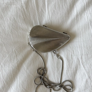 Detailed view of silver shell-shaped mini bag with radiant texture and snake chain