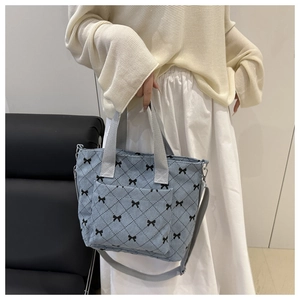 Détail du sac cabas en velours côtelé bleu clair avec motifs nœuds et bandoulière réglable