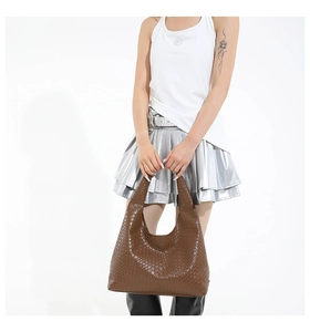 Detail of deep brown woven leather texture on a minimalist tote bag with top handle