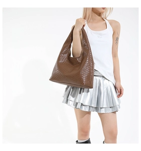 Detail of a brown woven texture tote bag showing its flexible silhouette and PU material