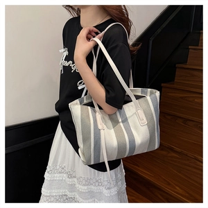Detailed view of large vertical striped canvas tote bag worn by model for daily commute