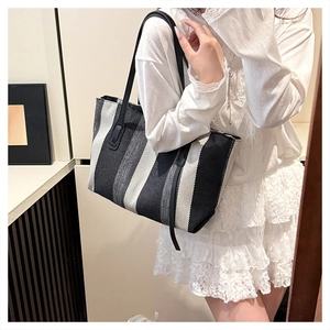 Detailed texture of large striped tote bag with leather straps and woven fabric finish