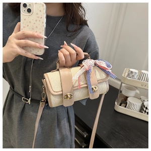 Détail d'un sac bandoulière tissé beige avec bordure en cuir et ruban de dentelle