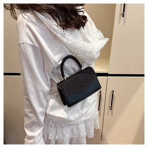 Détail d'un sac bandoulière chic à paillettes noires avec fine chaîne en métal sur modèle