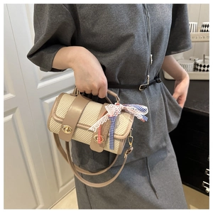 Détail du sac cylindrique tissé avec fermoirs dorés et nœud en dentelle bleue