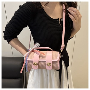 Détail du sac baril rose tissé avec des verrous dorés et un ornement de nœud en dentelle