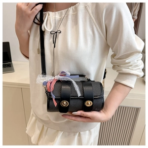 Detail of black woven shoulder bag featuring gold twist locks and a plaid lace bow accent