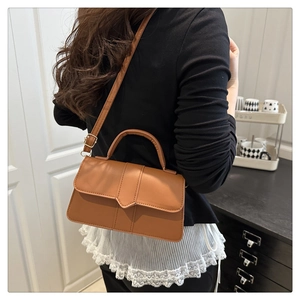 Détail d'un sac à bandoulière marron caramel avec rabat en V et coutures élégantes