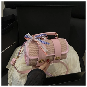 Close-up of pink leather crossbody bag with lace bow detail and dual gold turn-locks