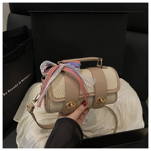 Detail of beige woven cylindrical handbag with tricolor lace bow and leather trim