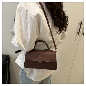 Détail d'un sac à main rectangulaire café avec cuir mat et ferrures dorées élégantes