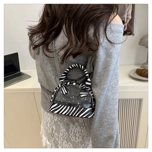 Zebra print shell bag in transparent PVC with silver chain strap shown in a lifestyle setting