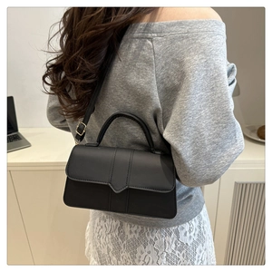 Détail du sac à bandoulière en cuir noir mat avec boucle pointue et garnitures dorées