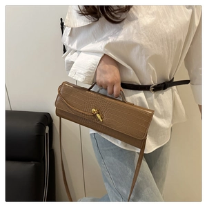 Borsa baguette marrone con stampa coccodrillo e chiusura a nodo dorato indossata dal modello