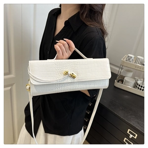 Dettaglio borsa baguette bianca motivo coccodrillo con elegante chiusura a nodo dorato