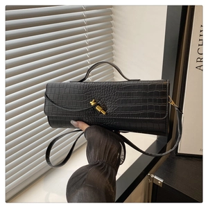 Detail of black crocodile pattern faux leather handbag with gold twist lock and slim handle