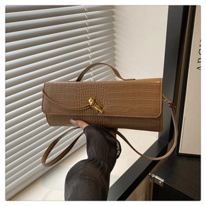 Detailed view of crocodile pattern texture and gold twist lock on brown leather handbag