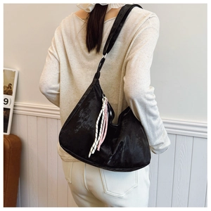 Detail of a black oversized tote bag with decorative woven zipper charms on a model