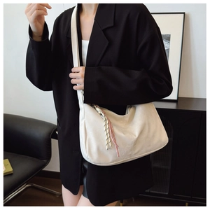 Detail of creamy white Hobo bag with textured leather and decorative tassel pendant