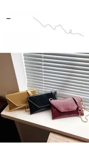 Detailed close-up of three envelope chain bags in gold, black and burgundy leather