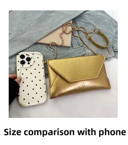 Detailed comparison of a gold metallic envelope bag size next to a smartphone