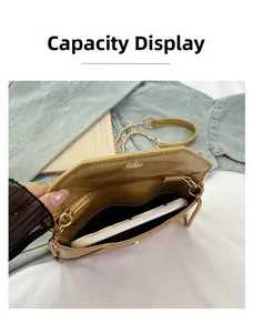 Interior capacity of golden metallic crossbody bag showing a white smartphone and pocket