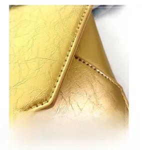 Macro view of gold wrinkled leather bag featuring detailed double-stitch edge craftsmanship