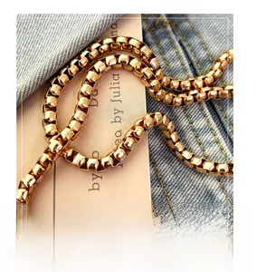 Close-up of golden box chain hardware on blue denim with illustrated card background