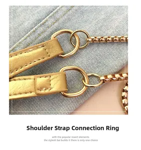 Detail of golden leather shoulder strap with metallic D-ring and chain on a crossbody bag