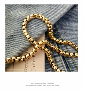 Close-up of a high-gloss golden metal box chain strap on blue denim fabric