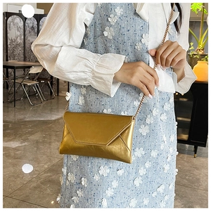 Nahaufnahme einer goldenen Metallic-Umschlagtasche mit feiner Kette und Verschluss