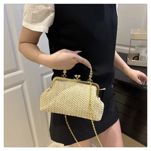 Détail de pochette en paille avec poignée fleurie dorée et bandoulière chaîne