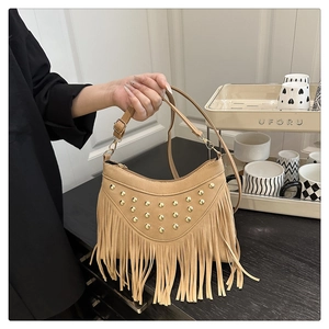 Detailed close-up of light brown suede tassel bag with golden rivets and adjustable strap