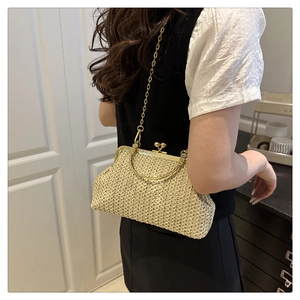Détail d'un sac à bandoulière en paille beige avec fermoir doré et chaîne sur mannequin