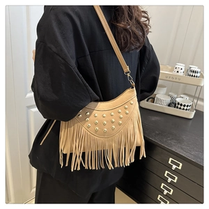 Detail of khaki bohemian saddle bag featuring decorative metal studs and long fringe tassels