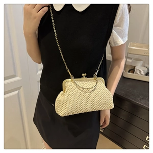 Détail du sac coquille en paille tressée beige avec fermoir doré et bandoulière chaîne