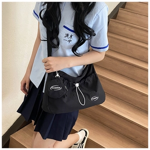Detail view of a black drawstring crossbody bag with fashion print and mini coin pouch