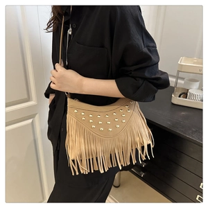 Close-up of khaki suede hobo bag with vintage tassels and golden stud decorations