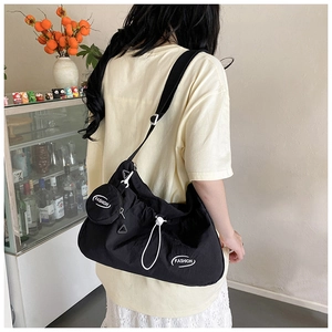Close-up of black crossbody bag with drawstring closure and matching mini coin purse detail