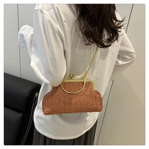 Détail d'un sac en paille tressée marron avec poignée dorée et bandoulière sur un mannequin