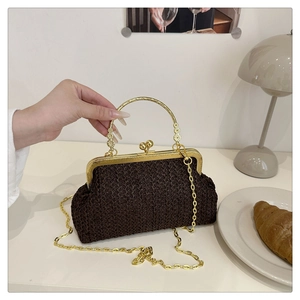 Détail d'un sac en paille tressée marron foncé avec fermoir doré et poignée fleurie