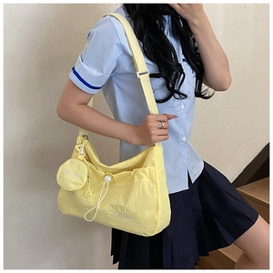 Detail of light yellow nylon crossbody bag with drawstring closure and mini coin purse