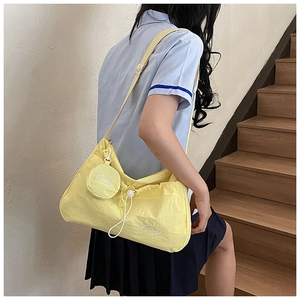 Close-up of bright yellow nylon crossbody bag with mini round coin pouch and FASHION print