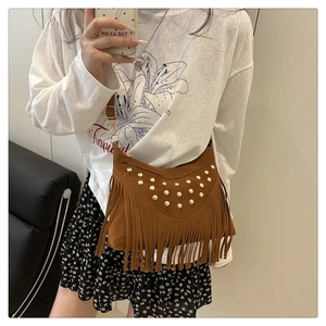 Close-up of vintage brown suede crossbody bag with gold studs and long tassel details