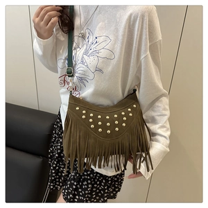 Detail of brown suede crossbody bag with long fringes and golden rivet studs