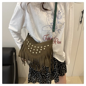 Detail of olive green suede saddle bag with gold studs and long fringe tassels