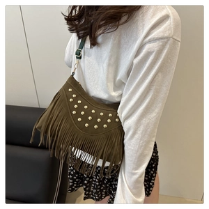 Detail of dark olive suede shoulder bag with boho fringe and gold rivet studs