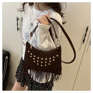 Detail of dark brown saddle bag with golden studs and long bohemian tassels